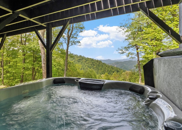 Un jacuzzi con vistas a un paisaje montañoso boscoso.