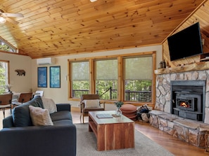 Una sala de estar acogedora con chimenea, techo de madera y ventanas amplias.