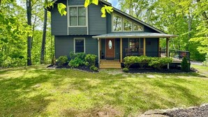 A two-story house with a front porch, surrounded by a well-maintained lawn and trees.