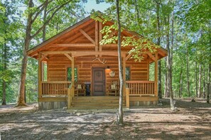 Une cabane rustique dotée d’un porche, de murs en bois et d’une enseigne accueillante.