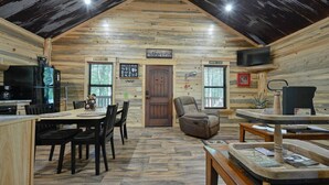 Un intérieur de chalet chaleureux avec un coin repas, une cheminée et un téléviseur.