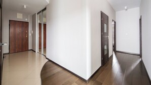 Um corredor moderno com teto curvo, portas de madeira e chão em mosaico.