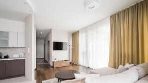 Uma sala de estar moderna com um sofá, uma mesa de centro e uma TV fixada na parede.