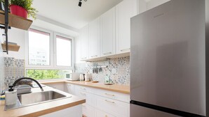Una cocina moderna con armarios blancos, un refrigerador de acero inoxidable y un ventanal que proporciona luz natural.