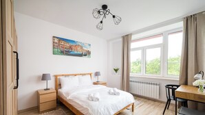Un dormitorio ordenado con cama de madera, mesitas de noche, un escritorio y una ventana con cortinas.