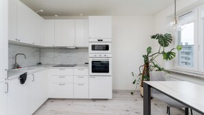 A modern kitchen with white cabinets, a marble backsplash, and a built-in oven.