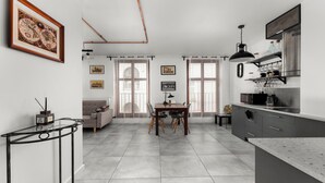 A modern kitchen with a dining area, featuring a large island, built-in appliances, and a view of the city. - Limanowskiego Modern Studio (Kraków)