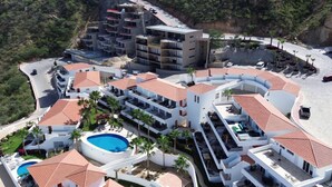 A resort with multiple buildings, a swimming pool, and a curved road. - Pedregal, 2 Pools, Quite, Ocean View, Walk to town (Cabo San Lucas)