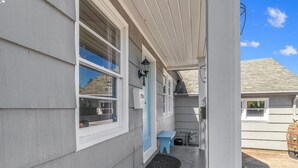 Una casa amb un porxo cobert, una porta blava i una petita zona d'estar a l'exterior.