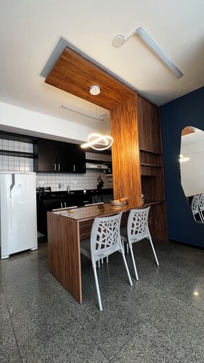 Een moderne keuken met een centraal eiland, witte stoelen en een houten accentmuur.