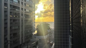 A multi-story building with a parking garage and a view of the sunset over the water.