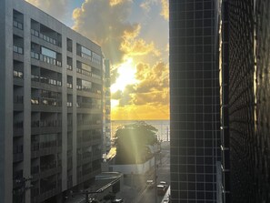 A multi-story building with a parking garage and a view of the sunset over the water.