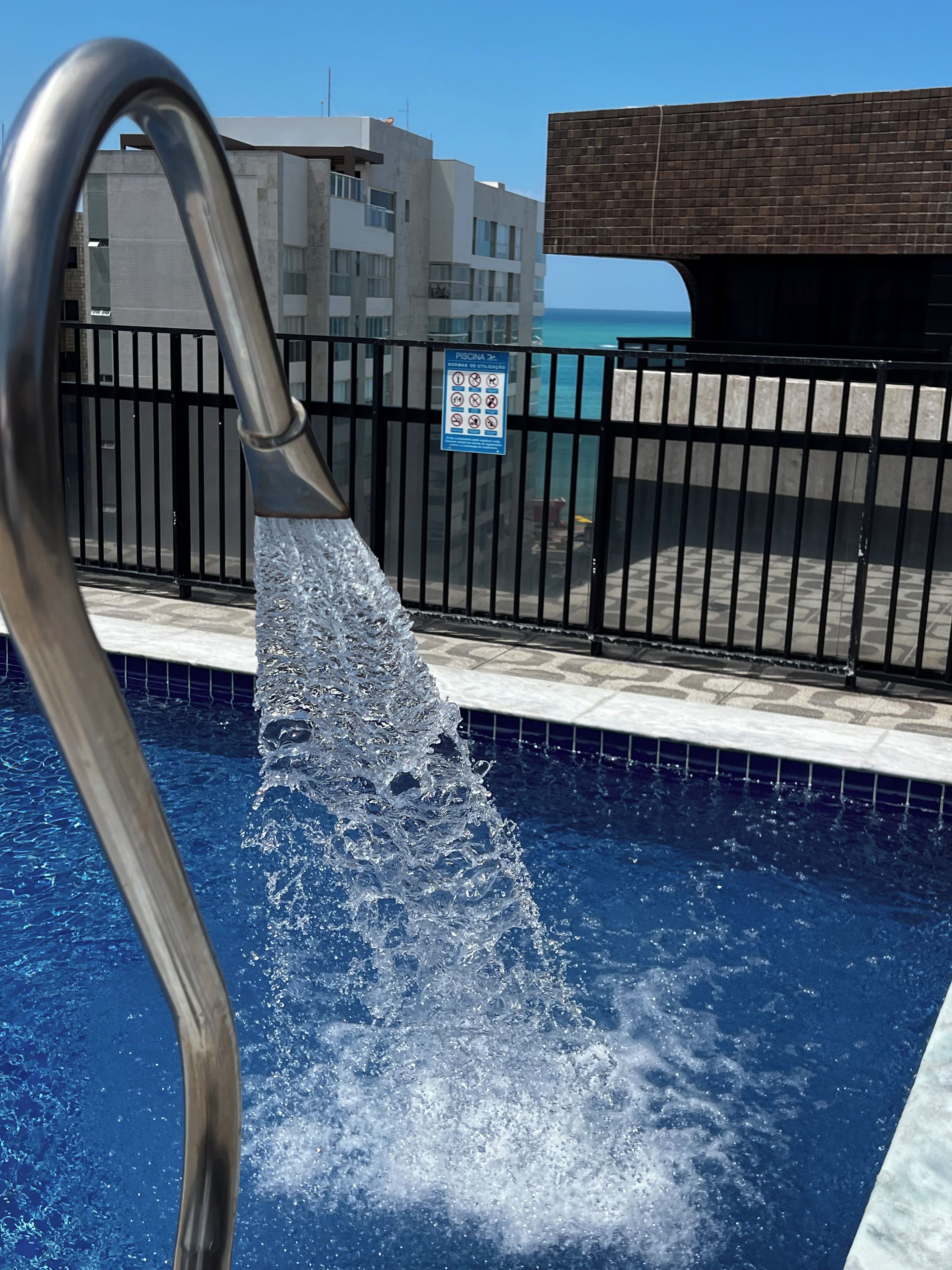 A swimming pool with a metal handrail and a black fence.
