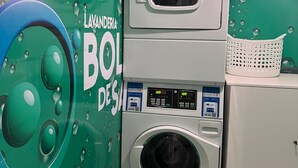 A laundry facility with a front-loading washer and dryer, a wall-mounted microwave, and a basket on the dryer.
