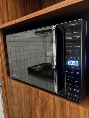 A modern microwave oven with a digital display, wooden cabinet, and a grid-patterned interior.