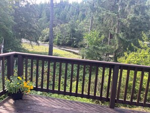 Une terrasse en bois avec une balustrade donnant sur une zone boisée.
