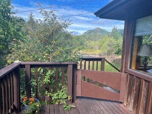 Une terrasse en bois avec une rambarde, un pot de fleurs et une vue sur un paysage montagneux.