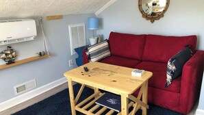 A cozy room with a red sofa, a wooden table, a lamp, and a mirror on the wall. - Charming, nautical themed 1-bedroom upstairs apartment in Washington ,NC (Washington)