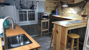 A compact kitchen with a wooden countertop, a sink, a small stove, and a bar area with stools. - Charming, nautical themed 1-bedroom upstairs apartment in Washington ,NC (Washington)