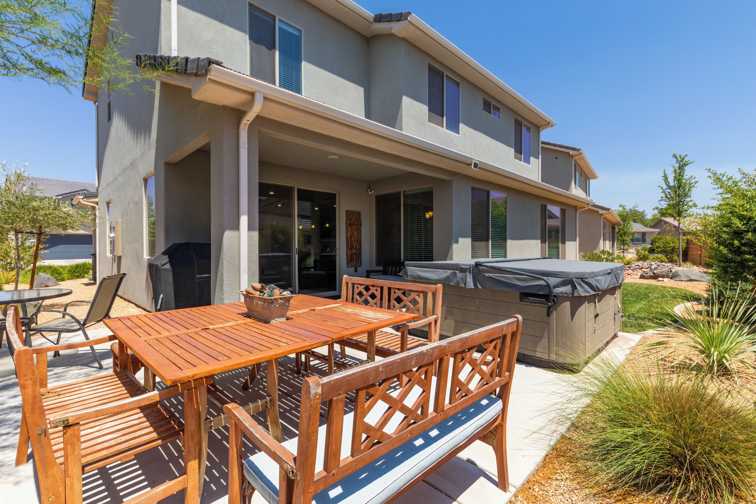 A two-story house with a covered patio area featuring a wooden table and chairs.