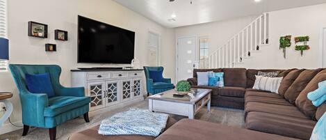 A living room with a ceiling fan, a flat-screen TV, a sofa, a coffee table, and a cabinet.