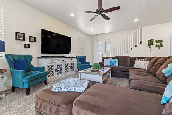 A living room with a ceiling fan, a flat-screen TV, a sofa, a coffee table, and a cabinet.