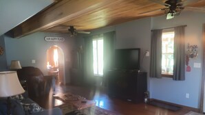 A living room with a sofa, a coffee table, a TV, and a ceiling fan.