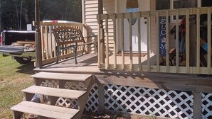 A wooden deck with a bench, a covered porch, and a welcome sign.