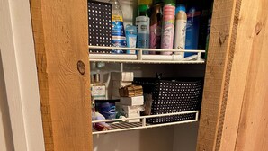 A storage closet with shelves holding toiletries and a white towel on the lower shelf.