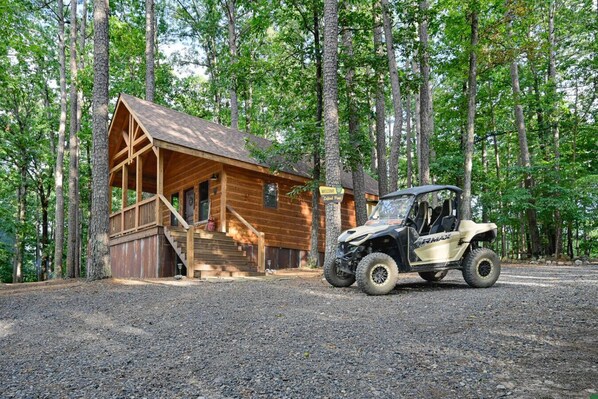 A wooden cabin with a porch and steps, surrounded by trees.