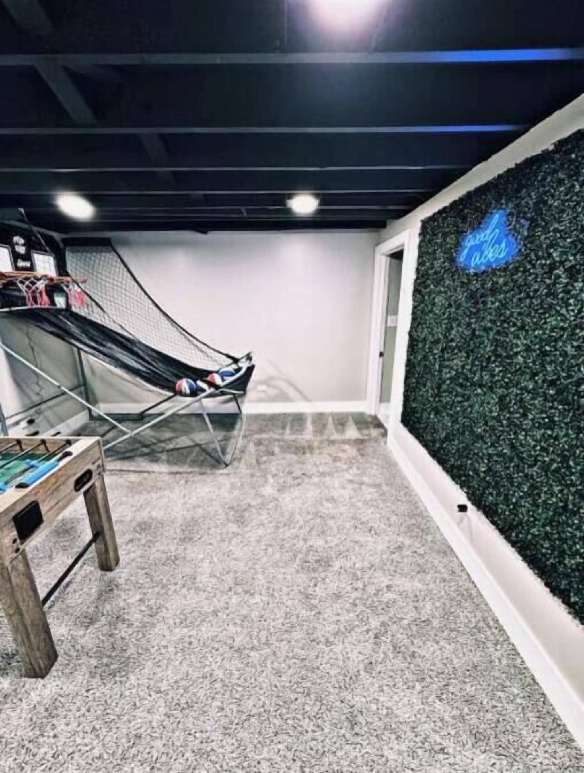 A room with a trampoline, a small table, and a wall with a green textured surface.