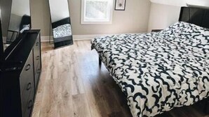Una camera da letto con un letto, una cassettiera, uno specchio e una finestra.