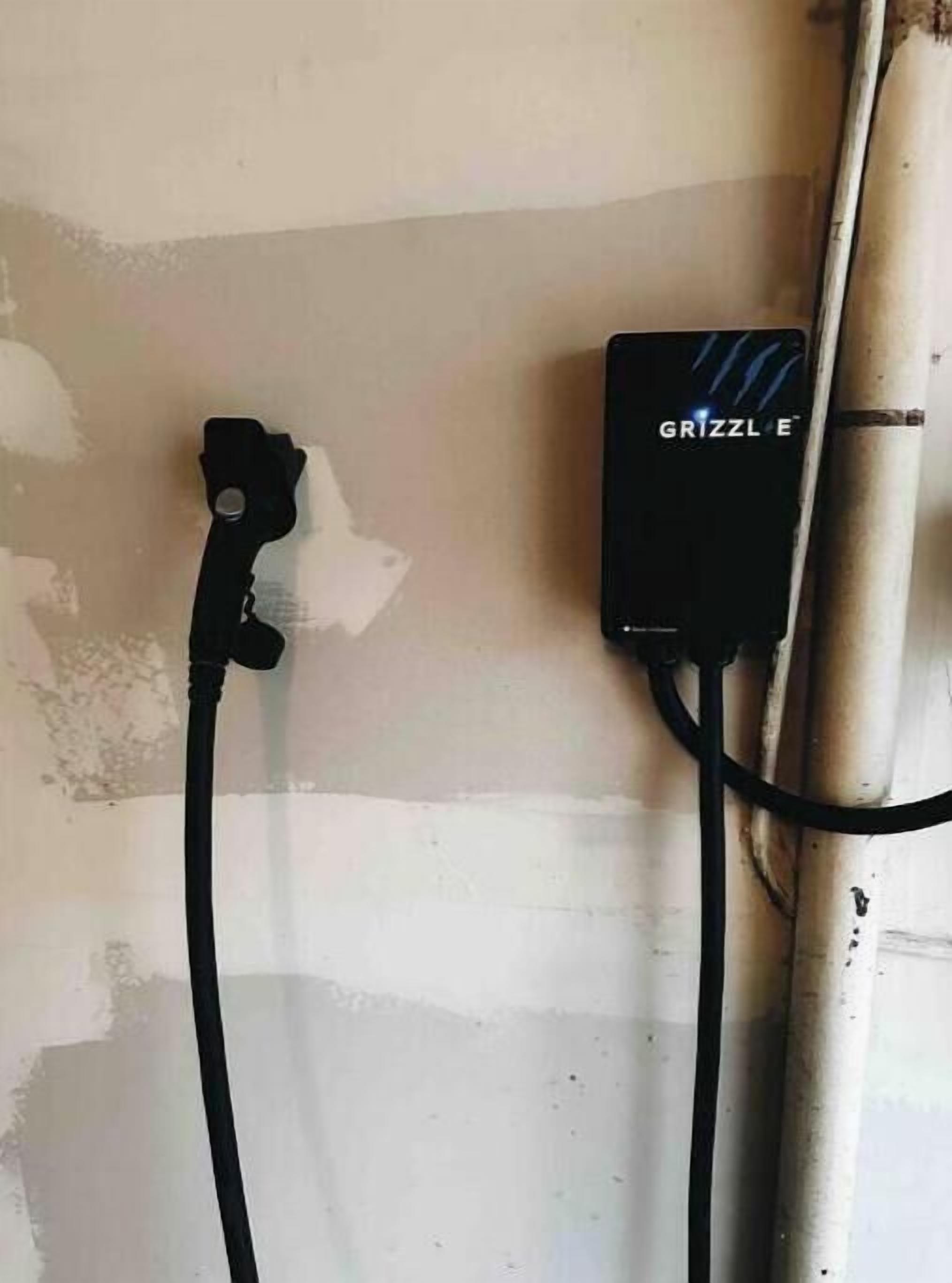 A GRIZZLE E power strip mounted on a wall with a cable connected to it.
