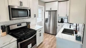 Una cucina moderna con mobili bianchi, elettrodomestici in acciaio inossidabile e pavimento in legno.