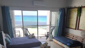 A room with two beds, a bench, and a view of the ocean. - CANCUN OCEANFRONT STUDIO SUNFLOWER CONDOMINIUM (Cancun)