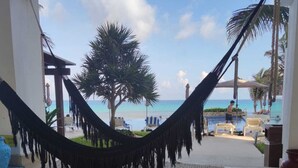 A hammock in a room with a view of the beach and palm trees. - CANCUN OCEANFRONT STUDIO SUNFLOWER CONDOMINIUM (Cancun)