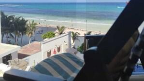 A view from a balcony overlooking a beach with clear skies and calm waters. - CANCUN OCEANFRONT STUDIO SUNFLOWER CONDOMINIUM (Cancun)