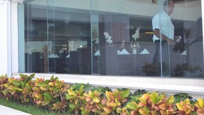 A modern building with large glass windows and a well-maintained garden with colorful foliage. - CANCUN OCEANFRONT STUDIO SUNFLOWER CONDOMINIUM (Cancun)