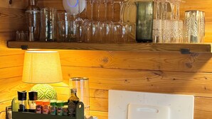 A kitchen with a microwave, a stove, and a shelf with glassware and spices.