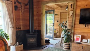 Interior acogedor de una cabaña con sofá a cuadros, chimenea, televisión y un letrero que dice 