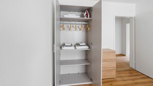 A walk-in closet with multiple shelves and hanging space, wooden flooring, and a white door. - Blueground | Basel-Iselin, balcony, nr Rhine (Basel)