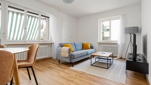 A modern living room with a sofa, coffee table, and TV stand. - Blueground | Basel-Iselin, balcony, nr Rhine (Basel)
