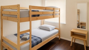 A bunk bed with a wooden frame, a bedside table, and a mirror. - Wynwood Hostel (Miami)
