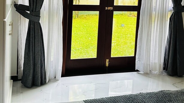 Ein Zimmer mit großem Fenster, Vorhängen und einem Bett.
