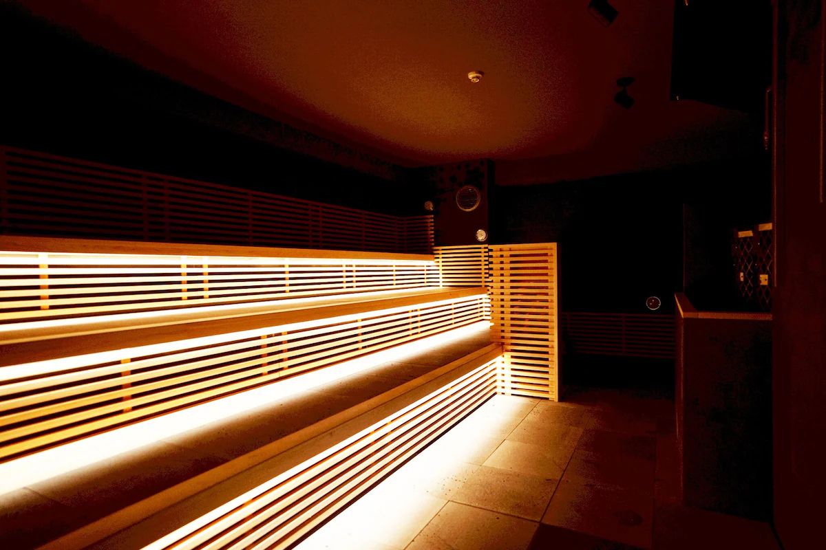 A dimly lit room with a long bench and a wall with horizontal slats.