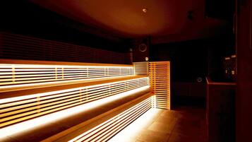 A dimly lit room with a long bench and a wall with horizontal slats.