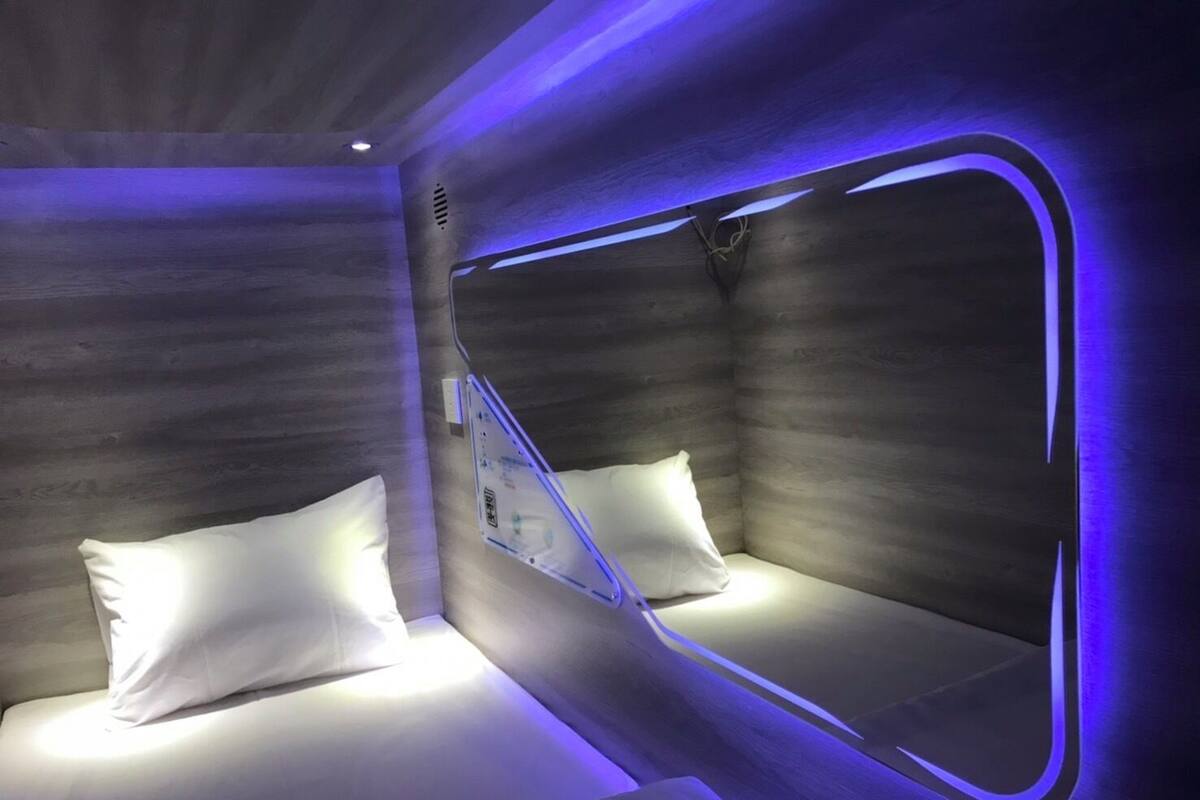 A modern room with a unique design, featuring a bed with a built-in headboard and a large mirror.