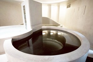 A modern, minimalist bathroom with a central circular water feature and a curved bench. - Sugoi Sauna & Stay Azabujuban Ekimae - Caters to Men (Tokyo)