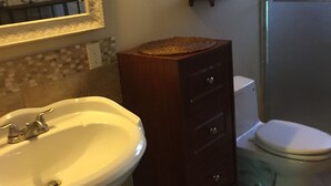 A bathroom with a white sink, a wooden vanity, a toilet, and a mirror with a decorative frame. - Furnished bedroom, bathroom, kitchen in a guard-gated community (Bell Canyon)