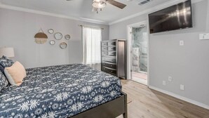 A bedroom with a bed, a ceiling fan, a TV, and a walk-in closet. - New Listing!  Breezy Palms (Aransas Pass)
